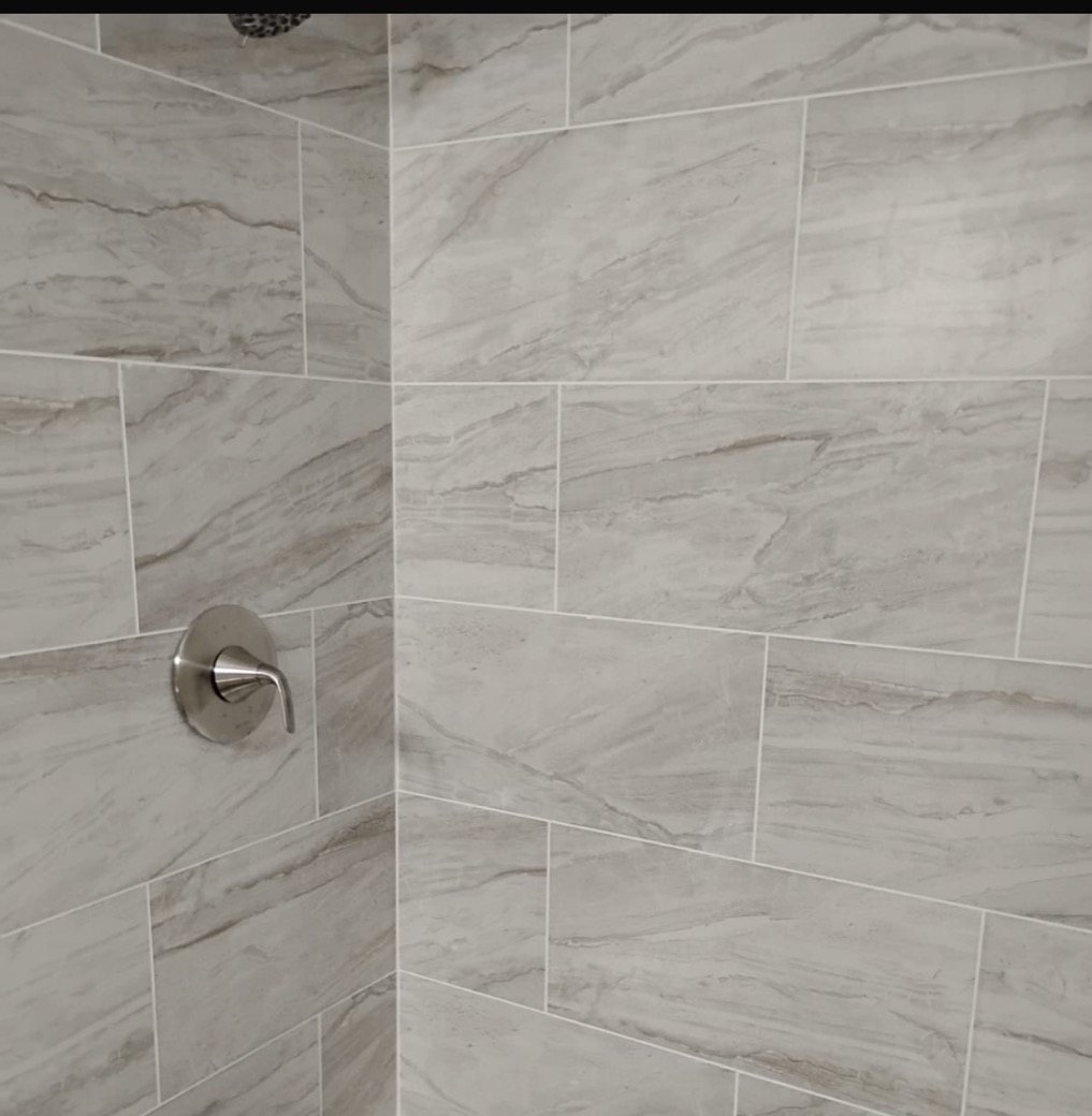 Tile shower wall with new brushed-nickel faucet and showerhead installed by GRA